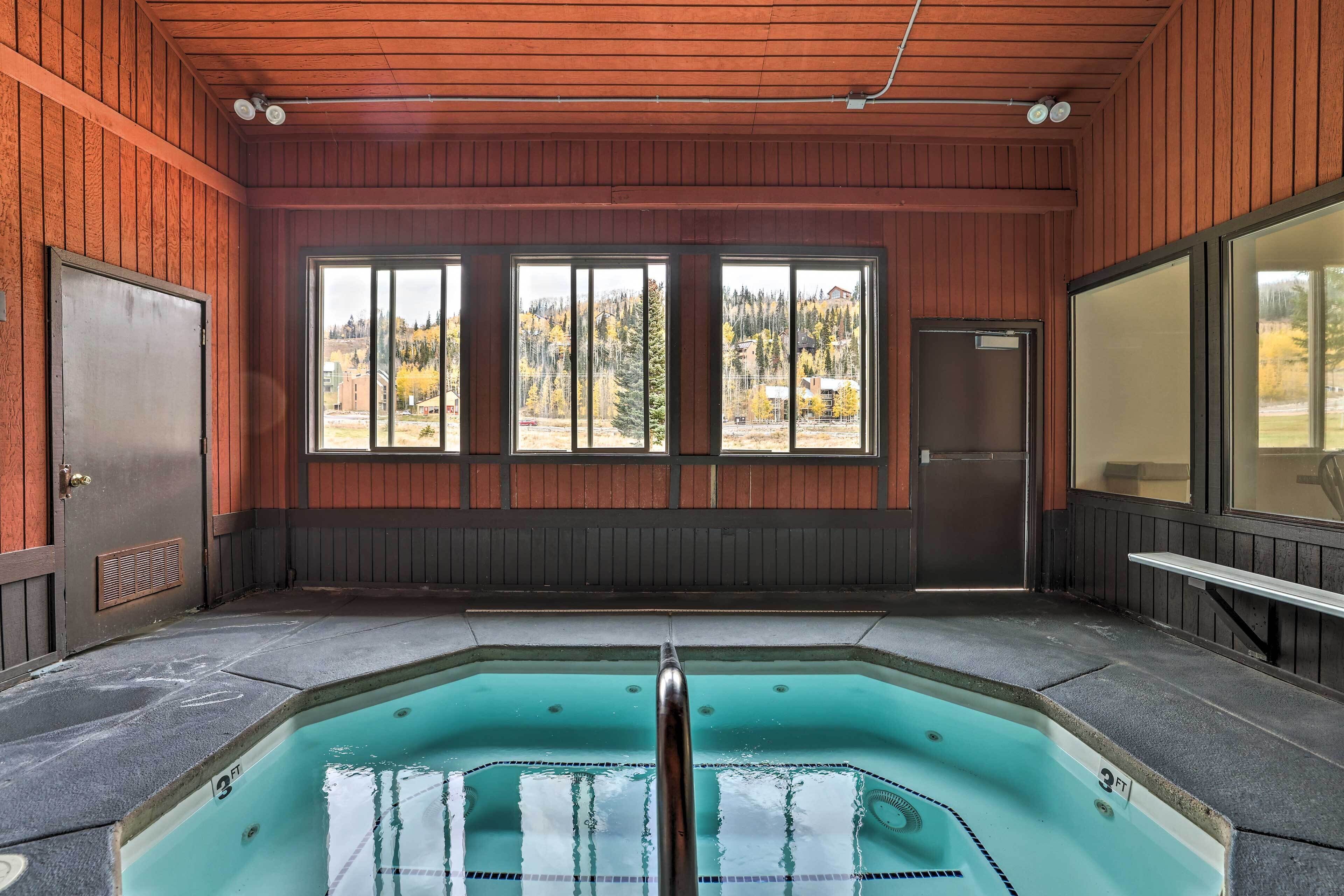 A hot tub with a view of a forested area through large windows.