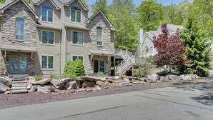 A multi-story stone house with a stone facade, multiple windows, and a front porch.