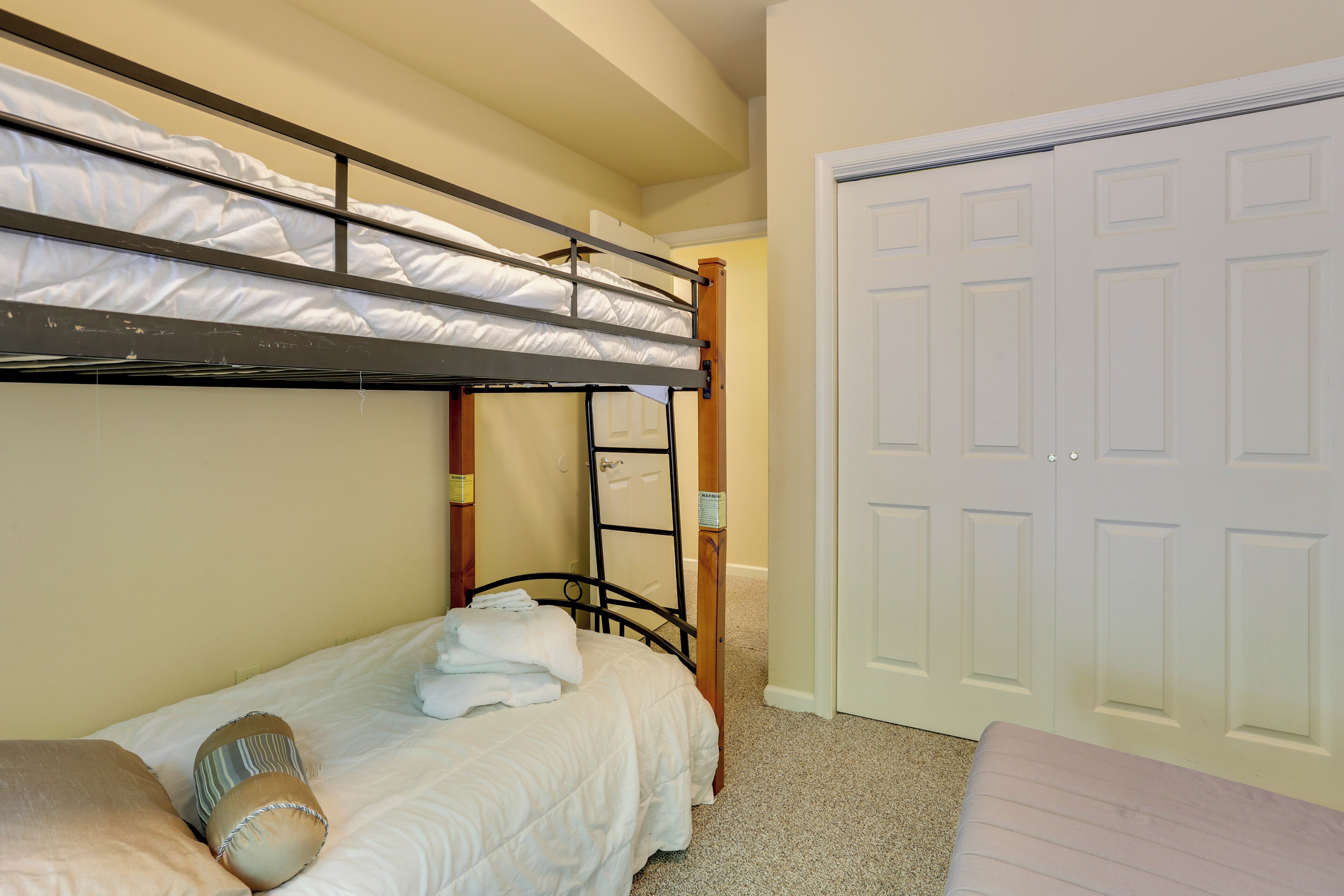 A bunk bed room with a door and a closet.