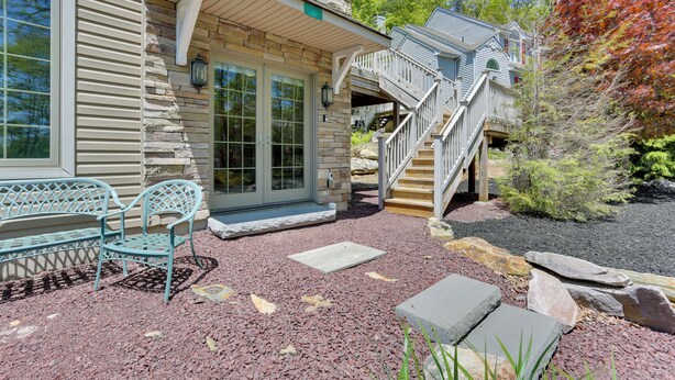 A stone house with a porch, a wooden staircase, and a bench.