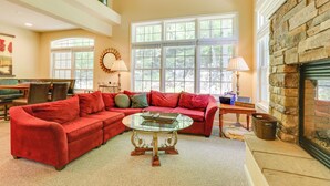 A spacious living room with a red sectional sofa, a glass coffee table, and a fireplace.