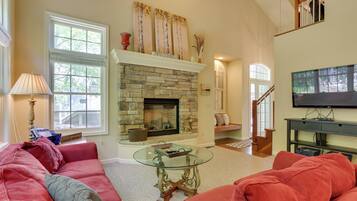 A living room with a stone fireplace, a glass coffee table, and a red sofa.