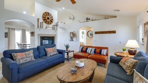 A spacious living room with a blue sofa, a wooden coffee table, and a fireplace. - Flagstaff Home w/ Hot Tub & Mountain Views (Flagstaff)