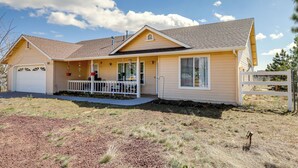 A single-story house with a front porch, a garage, and a fenced yard. - Flagstaff Home w/ Hot Tub & Mountain Views (Flagstaff)