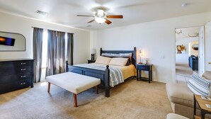 A bedroom with a bed, a bench, a nightstand, a dresser, a ceiling fan, and a door leading to another room. - Flagstaff Home w/ Hot Tub & Mountain Views (Flagstaff)