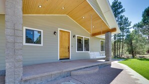 A modern house with a covered porch, stone pillars, and a well-maintained lawn. - Modern Show Low Home w/ BBQ & Fire Pit! (Show Low)