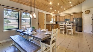 A spacious kitchen with wooden cabinets, a dining area with a bench, and a large window providing a view of the outdoors. - Modern Show Low Home w/ BBQ & Fire Pit! (Show Low)