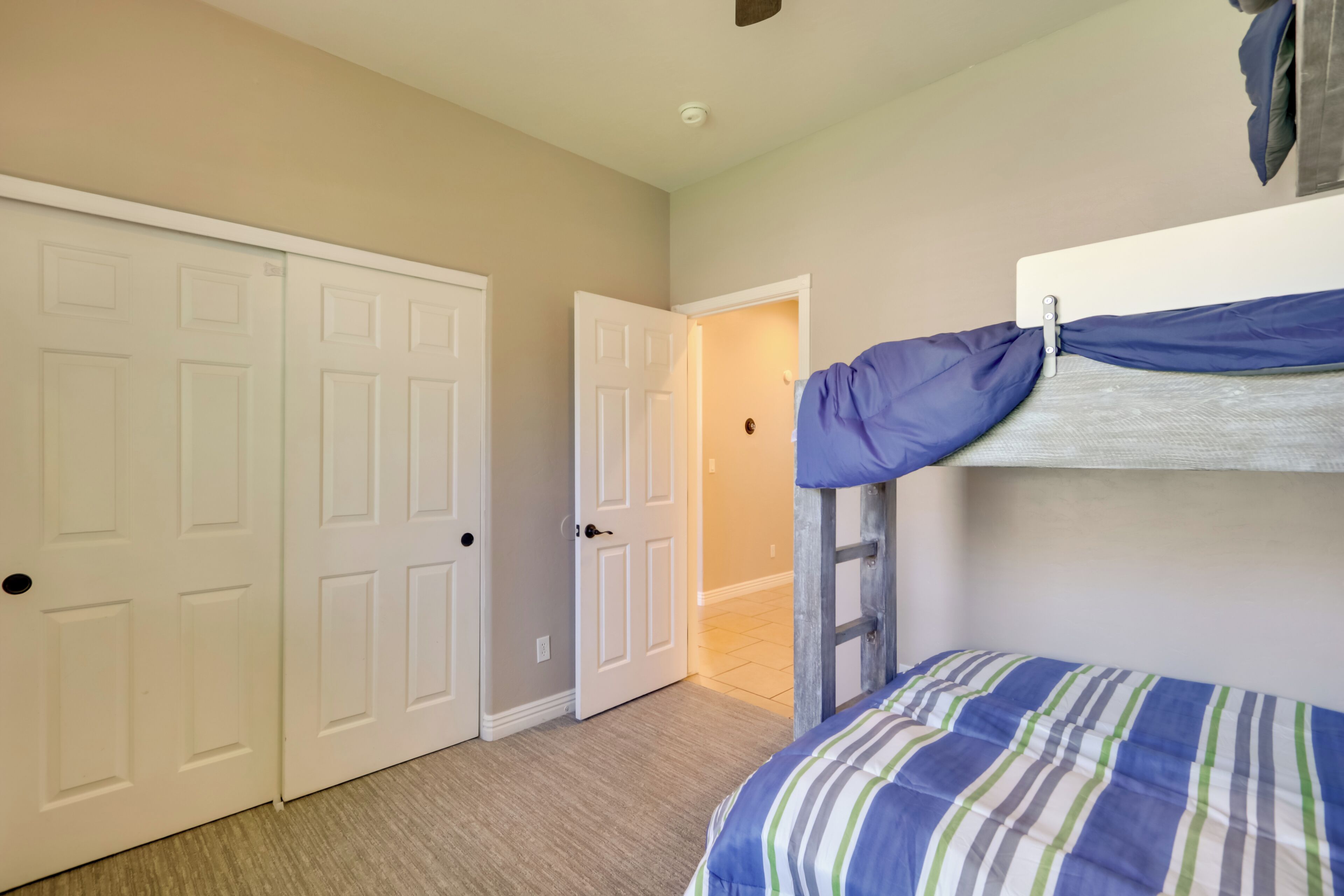 A bedroom with a bunk bed, a door, and a hallway.