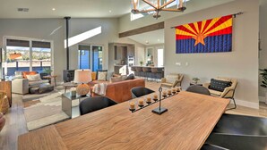 A spacious living area with a large wooden dining table, comfortable seating, and a view of the kitchen. - Flagstaff Home w/ Patios + Mount Humphries Views! (Flagstaff)