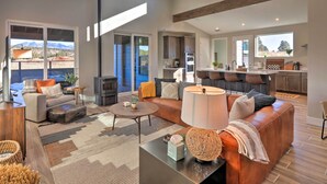 A spacious living area with a large sofa, coffee table, and a view of the mountains. - Flagstaff Home w/ Patios + Mount Humphries Views! (Flagstaff)