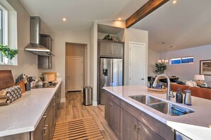 A modern kitchen with stainless steel appliances, a large island with a sink, and wooden cabinets. - Flagstaff Home w/ Patios + Mount Humphries Views! (Flagstaff)