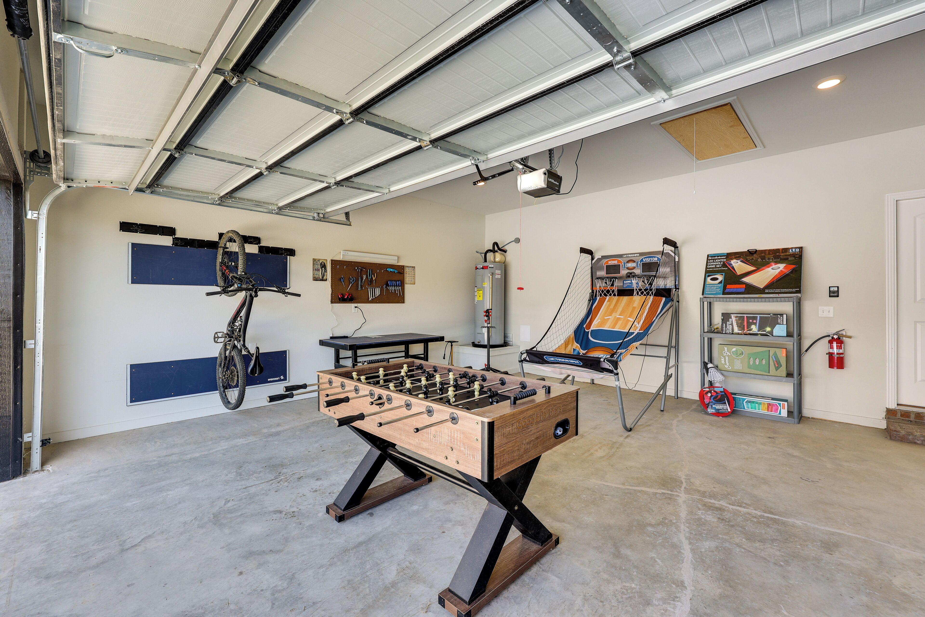 A spacious indoor area with a foosball table, a bicycle, and a ping pong table.