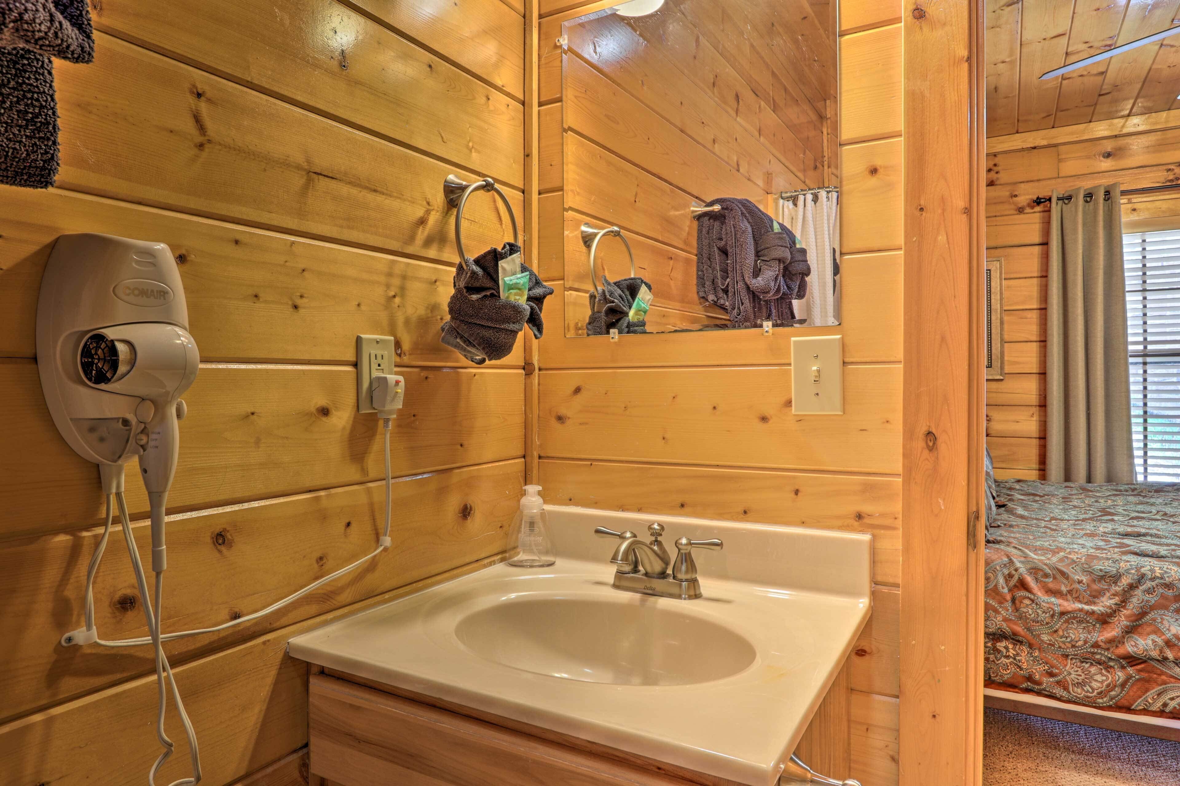 A wooden cabin bathroom with a sink, towel rack, and a hairdryer.