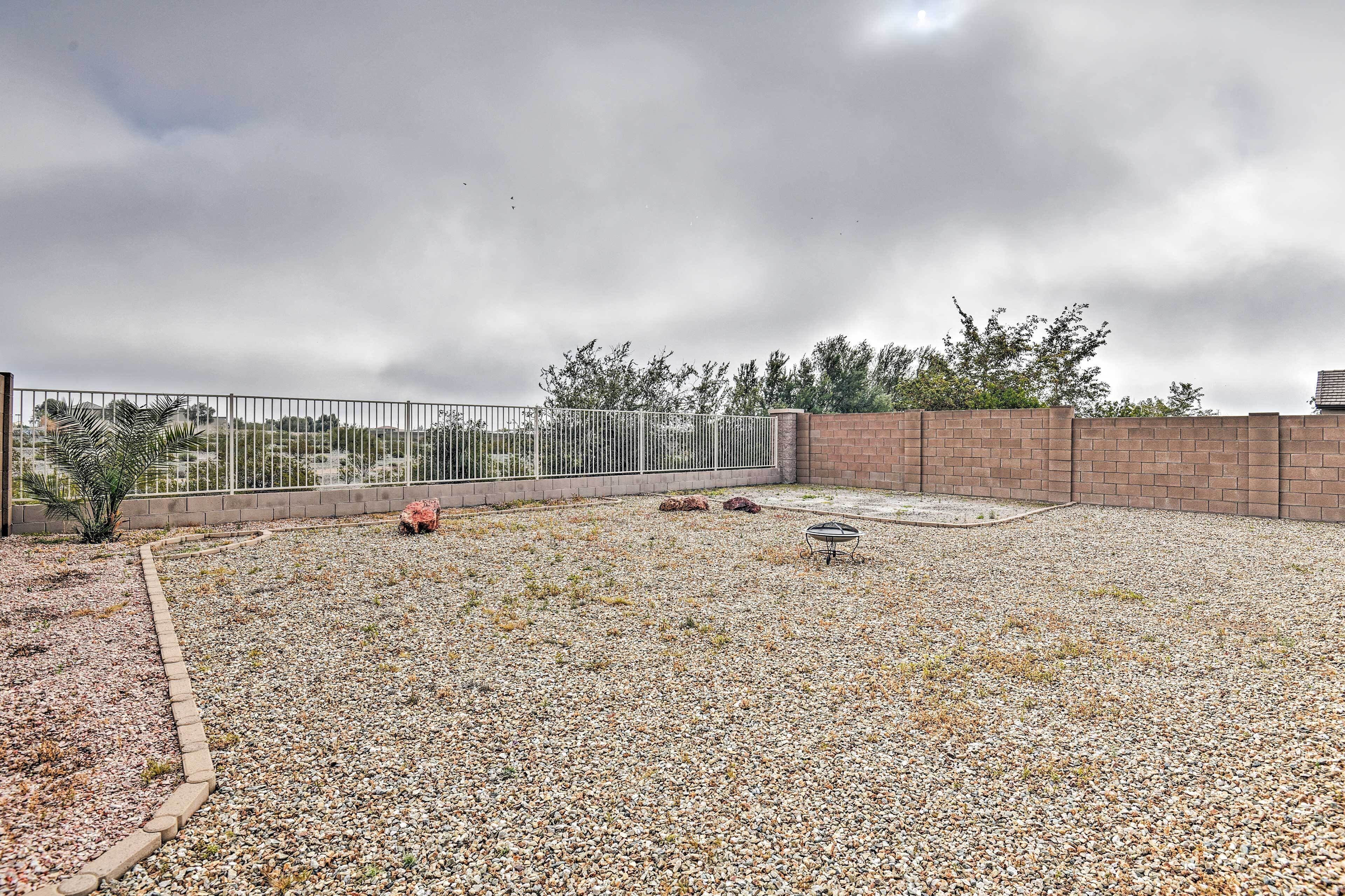 A rooftop patio with a gravel ground, a metal fence, and a brick wall.
