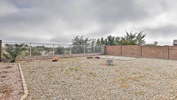 A rooftop patio with a gravel ground, a metal fence, and a brick wall.