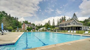 A rectangular swimming pool with a tiled edge, surrounded by lounge chairs and umbrellas, with a building in the background. - Bromley Mountain Escape w/ 2 Balconies: Hike & Ski (Peru)