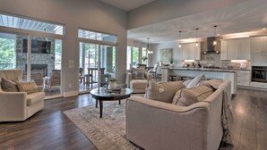 A spacious living room with a fireplace, a dining area, and a kitchen with white cabinets and a stone backsplash. - Boat Dock, Game Room! Multi-level Osage Beach Home (Osage Beach)