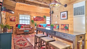 Un interior de cabaña acogedor con paredes de madera, un comedor, un sofá y una mesa de centro.