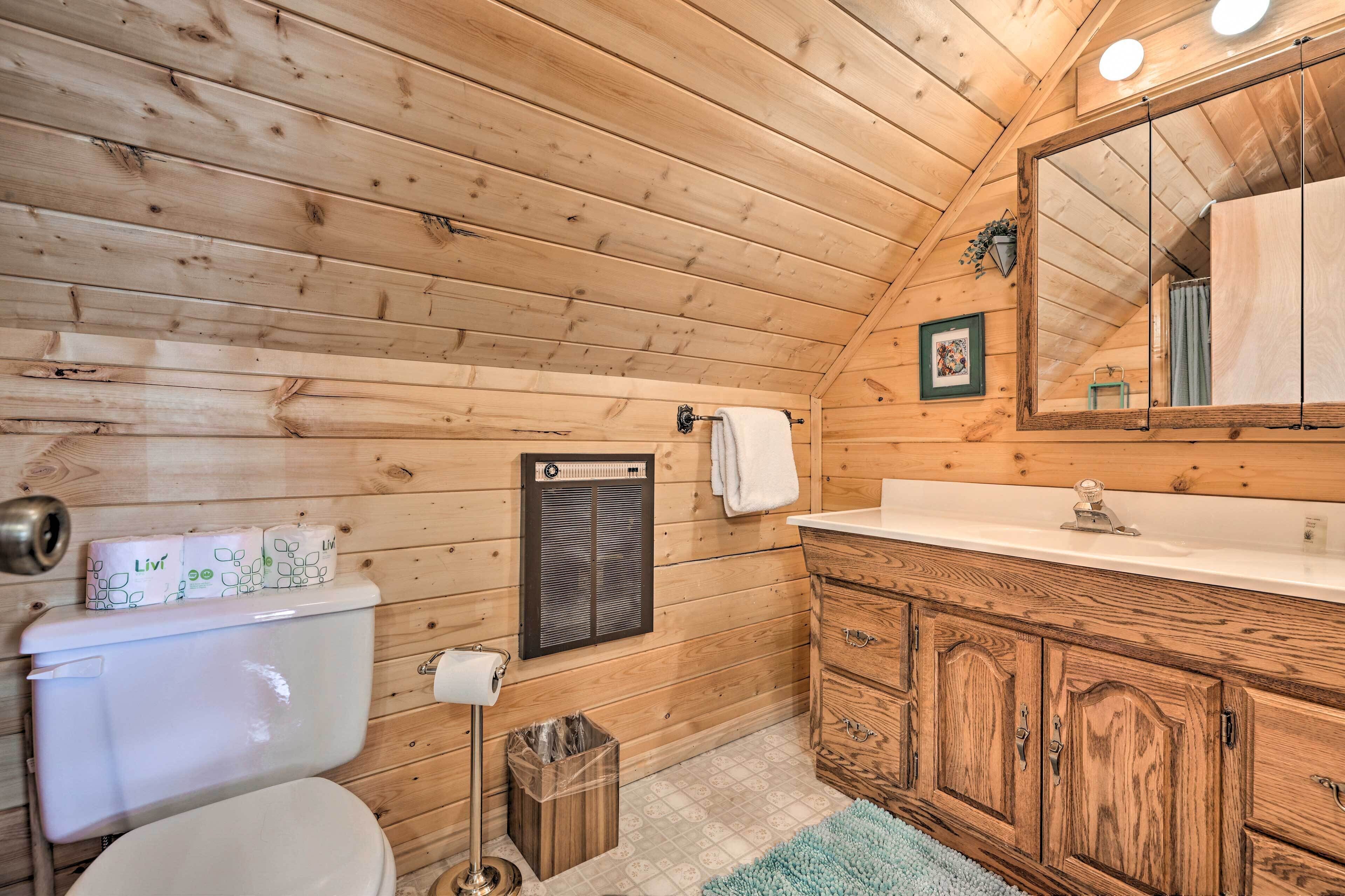 Un baño con paneles de madera, un inodoro, un lavabo y un espejo.