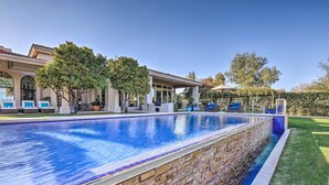 A swimming pool with a stone border, a covered patio area, and a well-maintained lawn. - Lavish Paradise Valley Home w/ Sports Court & Pool (Paradise Valley)