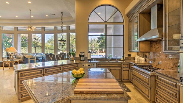 A spacious kitchen with a large island, granite countertops, and a view of the outdoors. - Lavish Paradise Valley Home w/ Sports Court & Pool (Paradise Valley)
