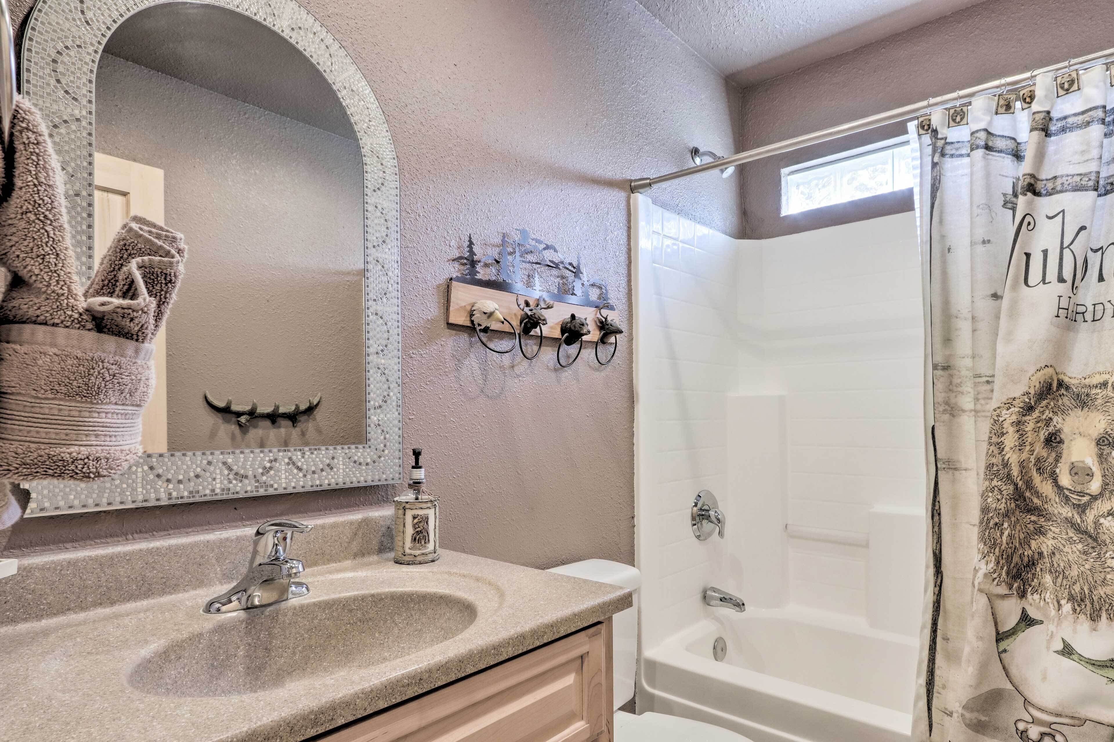 Une salle de bain dotée d’un grand miroir, d’un lavabo, d’une douche et d’un porte-serviettes agrémenté d’objets décoratifs.