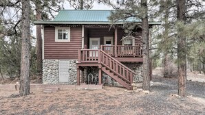 A cabin with a stone foundation, wooden exterior, and a green roof. It features a wooden staircase leading to a porch with a railing. - Fire Pit + Game Room: Heber-overgaard Cabin! (Overgaard)
