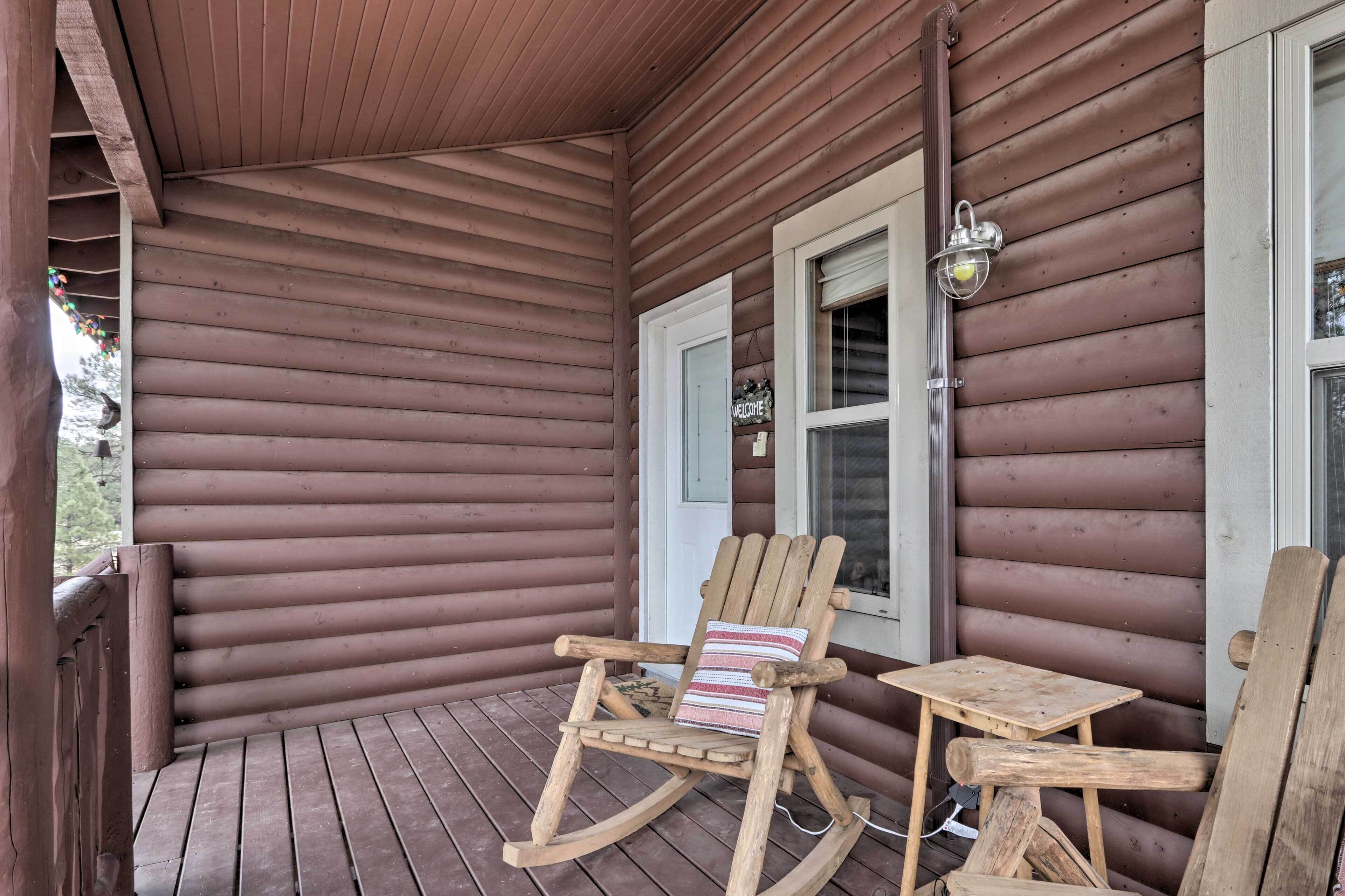 A wooden porch with a rocking chair and a small table.