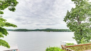 A wooden deck overlooking a calm lake with distant hills and a cloudy sky. - Deck & Boat Dock: Lakefront Getaway in Camdenton (Camdenton)