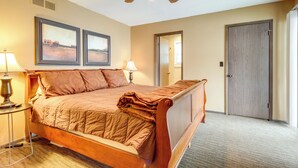 A hotel room with a wooden bed, two bedside lamps, a ceiling fan, and two framed pictures on the wall. - Deck & Boat Dock: Lakefront Getaway in Camdenton (Camdenton)