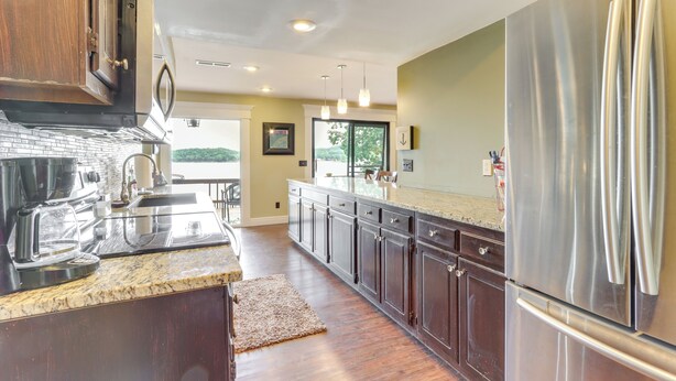 A modern kitchen with dark wood cabinets, stainless steel appliances, and a granite countertop. - Deck & Boat Dock: Lakefront Getaway in Camdenton (Camdenton)