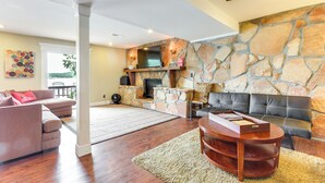 A spacious living room with a stone fireplace, a television, and a comfortable seating area. - Deck & Boat Dock: Lakefront Getaway in Camdenton (Camdenton)