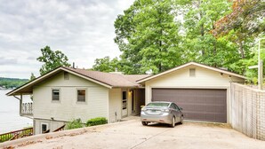 A two-story house with a garage, a driveway, and a view of a lake. - Deck & Boat Dock: Lakefront Getaway in Camdenton (Camdenton)
