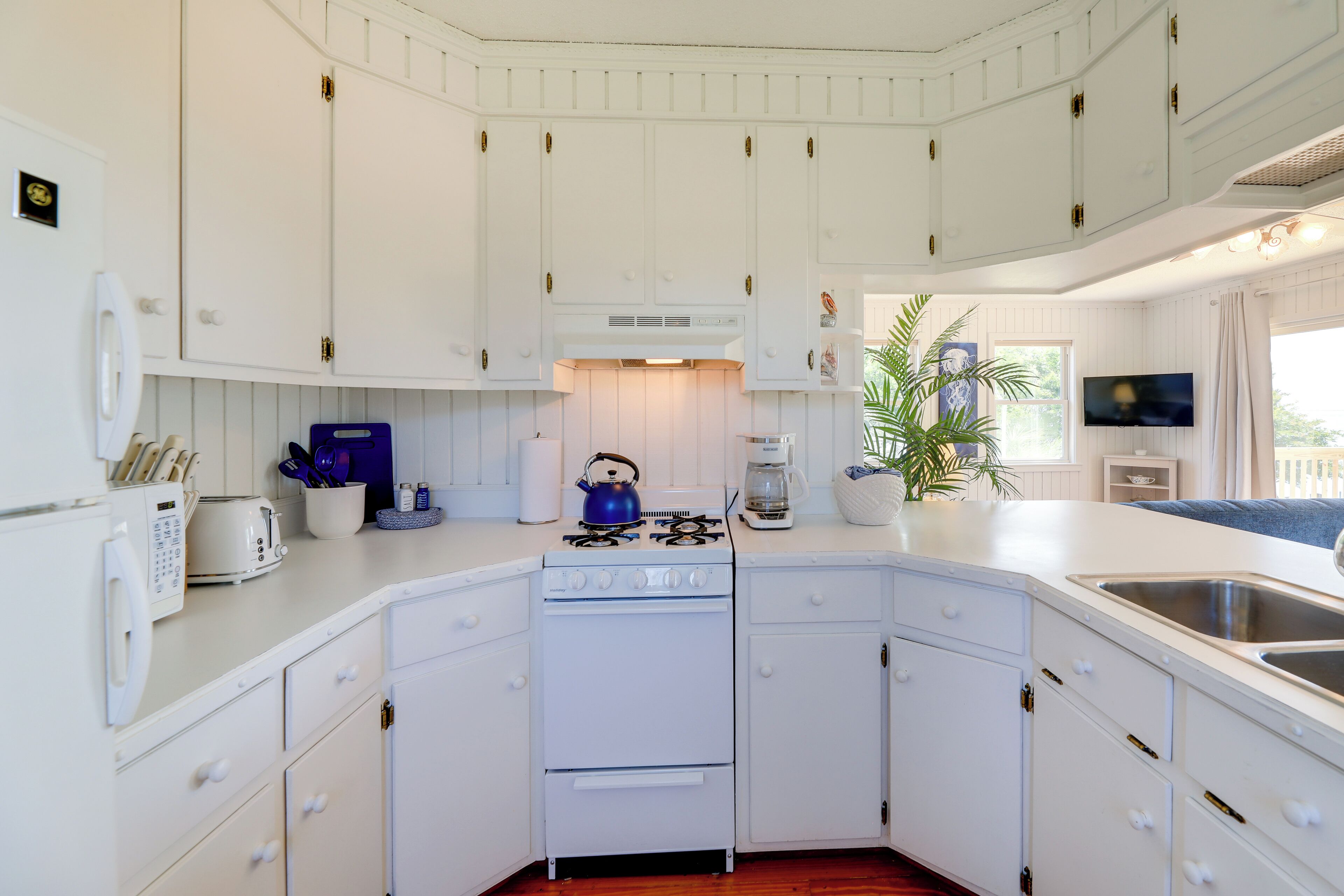 A kitchen with white cabinets, a stove, a toaster, and a coffee maker.