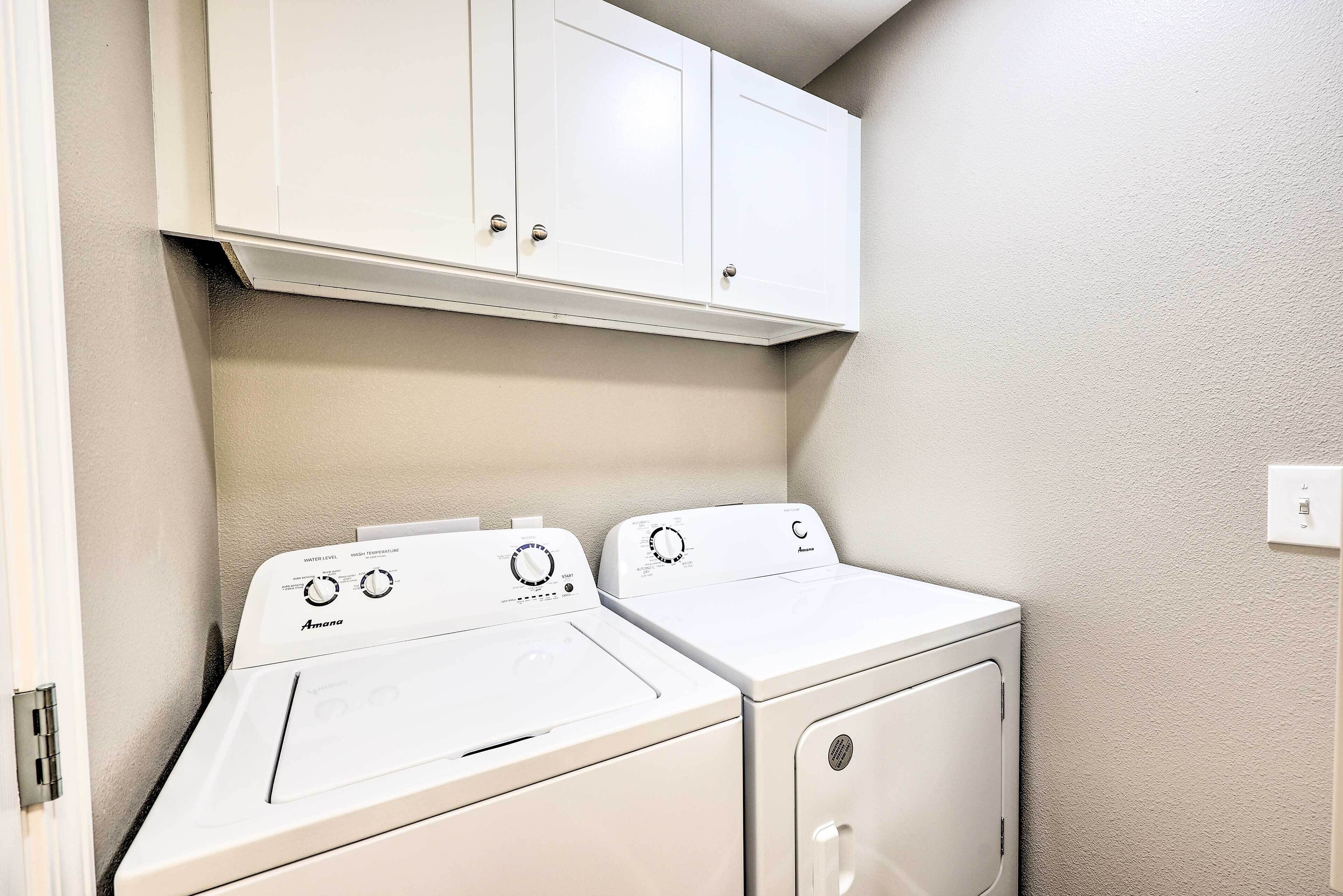 A laundry area with two white washing machines and a cabinet above them.