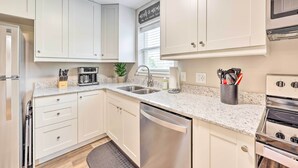 A modern kitchen with white cabinets, stainless steel appliances, and a granite countertop.