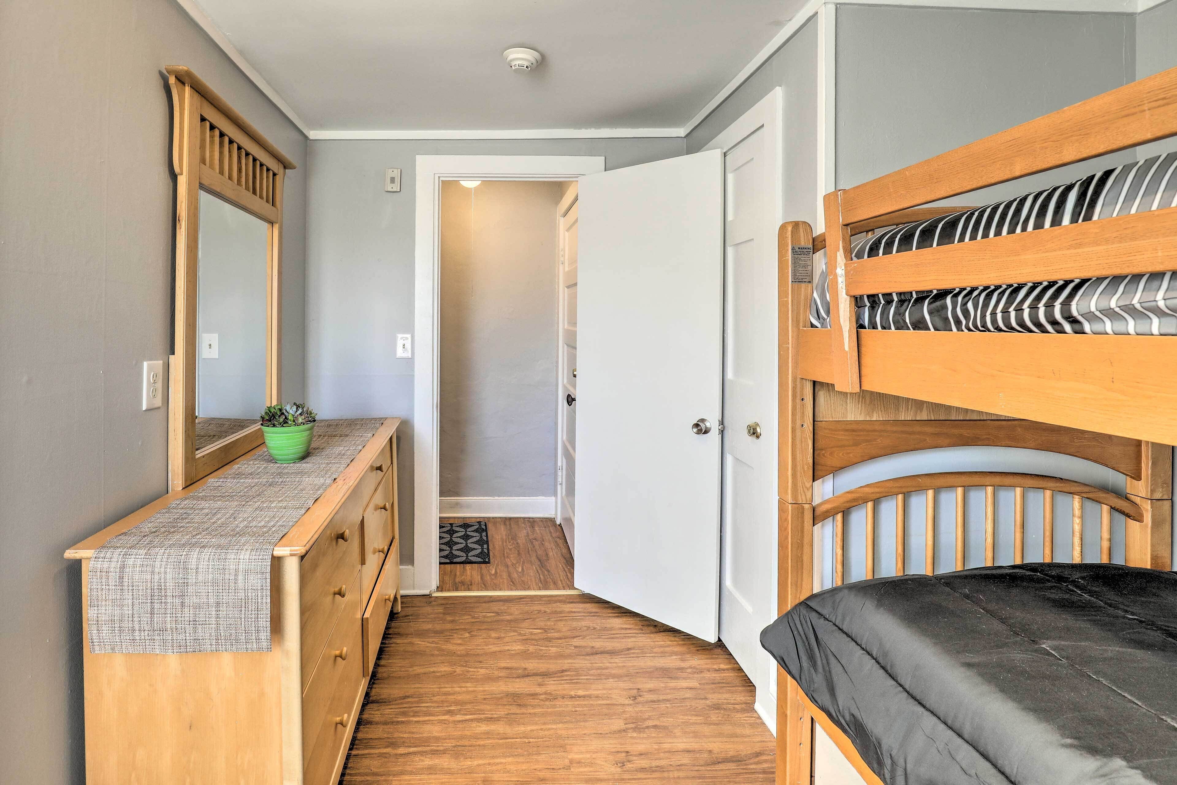 A compact room with a bunk bed, a wooden dresser with a mirror, and a small potted plant.