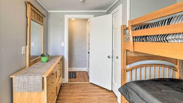 A compact room with a bunk bed, a wooden dresser with a mirror, and a small potted plant.
