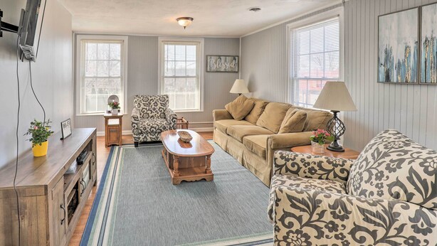 A living room with a sofa, armchairs, a coffee table, a lamp, and a TV. - Downtown Canandaigua Apt: 1 Mi to Lake & Pier! (Canandaigua)