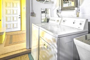 A laundry area with a front-loading washer and dryer, a door with a geometric pattern, and a mirror on the wall. - Venice Home w/ Private Pool, 7 Mi to Beach! (Venice)