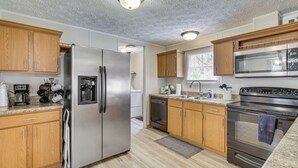 A modern kitchen with stainless steel appliances, wooden cabinets, and a window providing natural light.