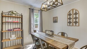 A dining area with a wooden table, metal chairs, a metal shelf unit, and a decorative light fixture.
