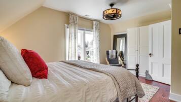 Une chambre avec un grand lit, un ventilateur de plafond et une vue sur l’extérieur par une fenêtre munie de rideaux.