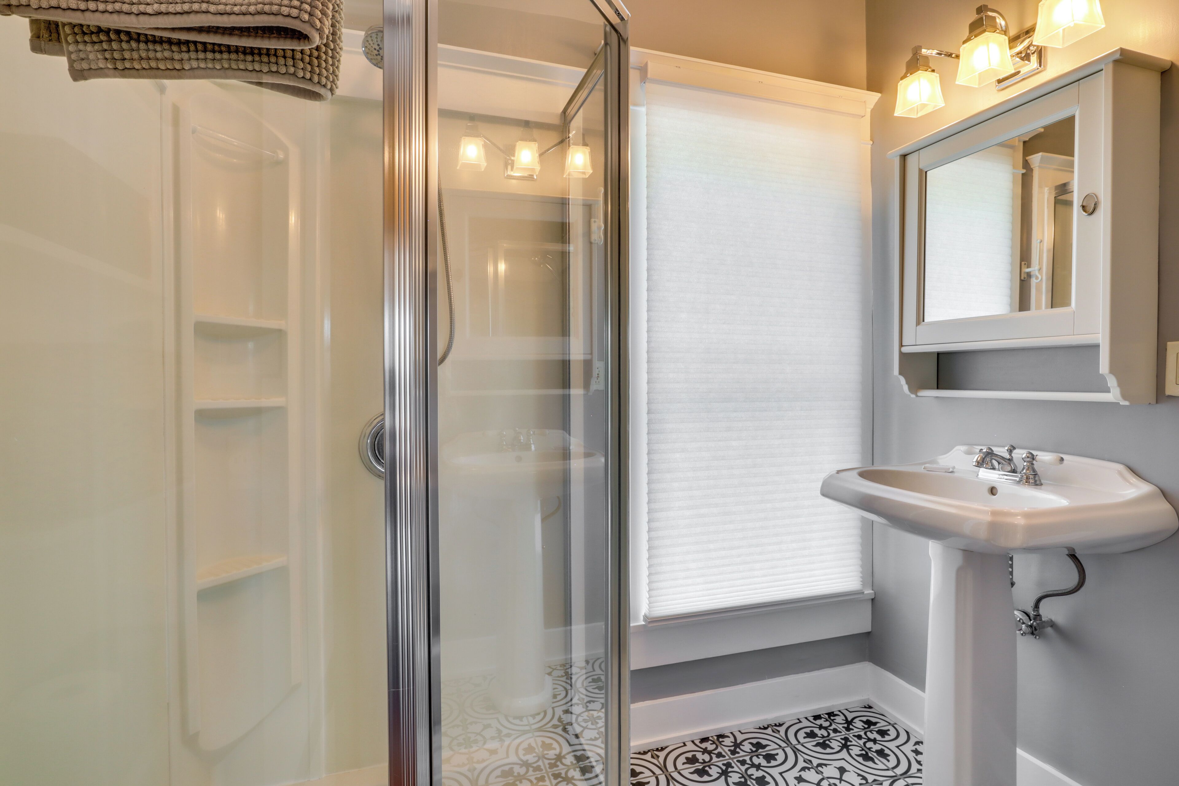 A bathroom with a glass shower enclosure, a white sink, and a mirror above the sink.