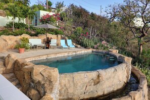 A swimming pool with a natural rock border, surrounded by lounge chairs and a table. - 'sea La Vie' - Waterfront St Thomas Escape w/ Pool (St. Thomas)
