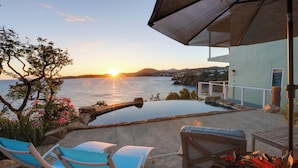 A sunlit outdoor area with a pool, lounge chairs, and a view of the sea at sunset. - 'sea La Vie' - Waterfront St Thomas Escape w/ Pool (St. Thomas)