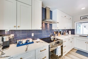 A modern kitchen with white cabinets, a stainless steel range, and a blue-tiled backsplash.