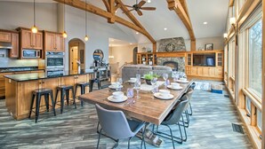A spacious kitchen with wooden beams, a dining area with a large table set for six, and a stone fireplace. - Dock, Hot Tub & Game Room: Luxe Lake Latoka Home (Alexandria)