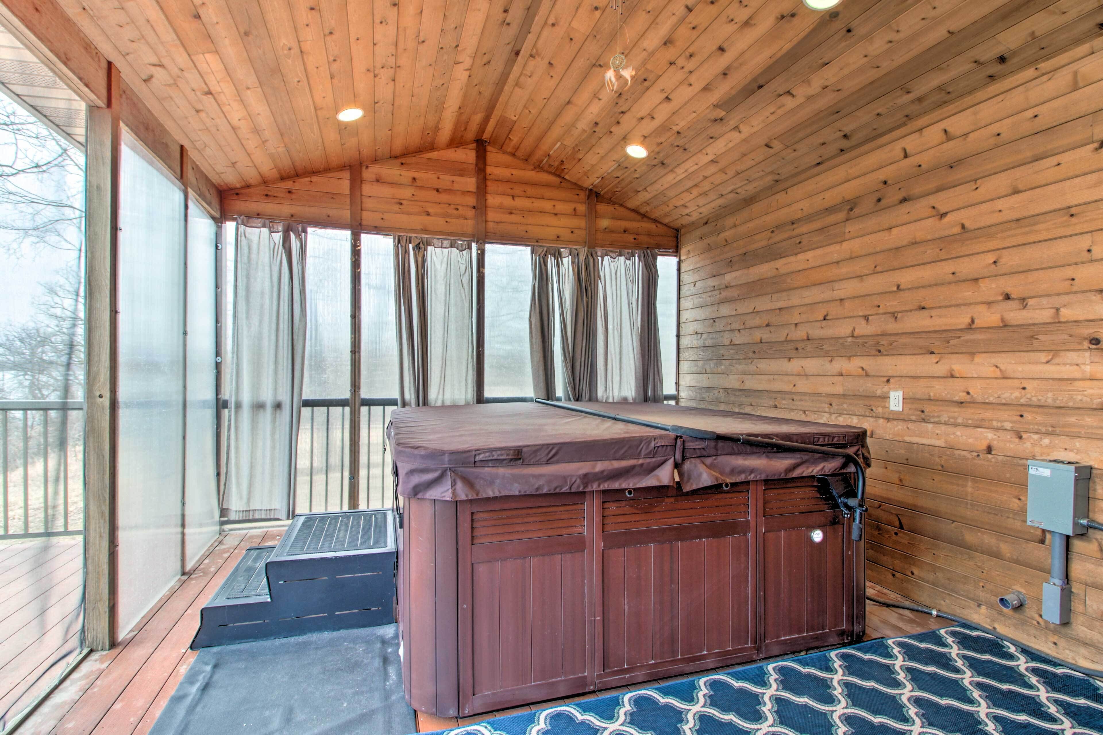 Sala de sauna com teto de madeira, mesa de massagem e uma grande janela com cortinas.