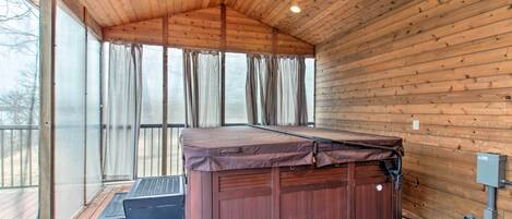 Sala de sauna com teto de madeira, mesa de massagem e uma grande janela com cortinas.